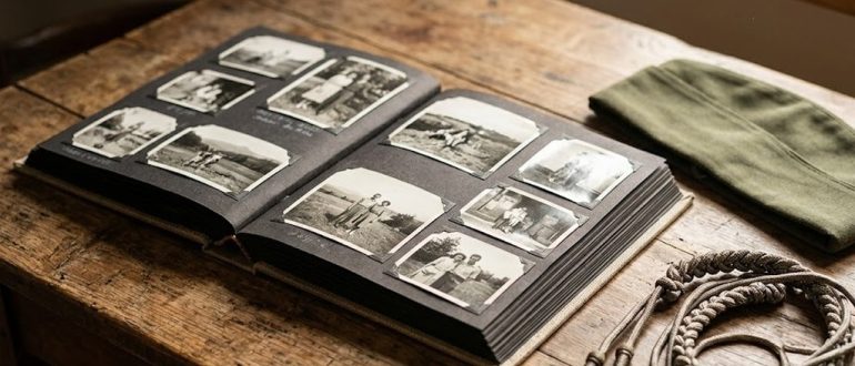 Самодельный фотоальбом и аккуратно сложенная фуражка на деревянном столе